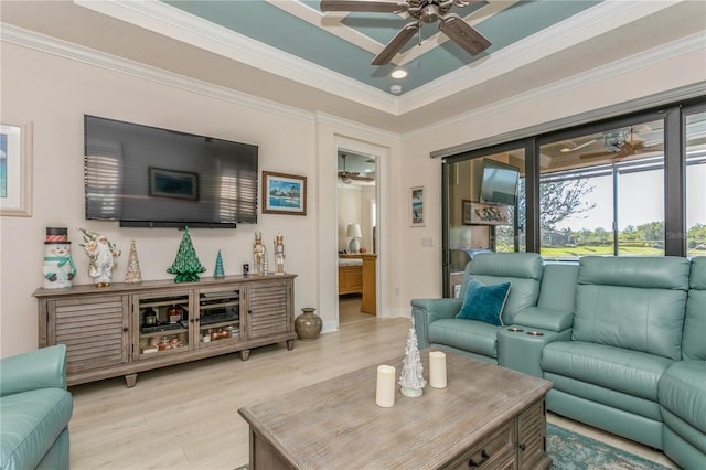 living room featuring a raised ceiling, ceiling fan, crown molding, and light hardwood / wood-style flooring