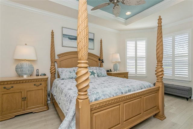 bedroom with a tray ceiling, ceiling fan, light wood-type flooring, and ornamental molding