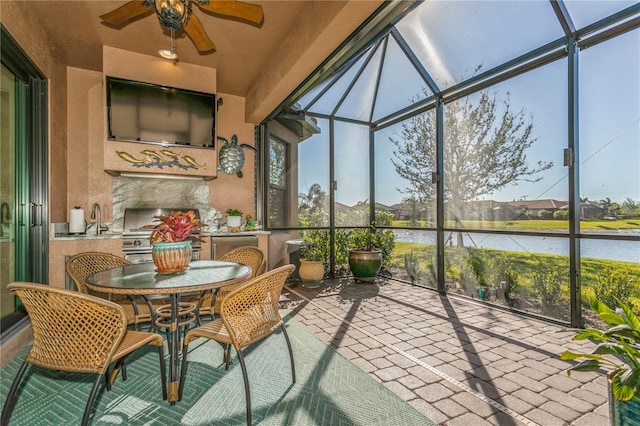 sunroom featuring sink, ceiling fan, and a water view