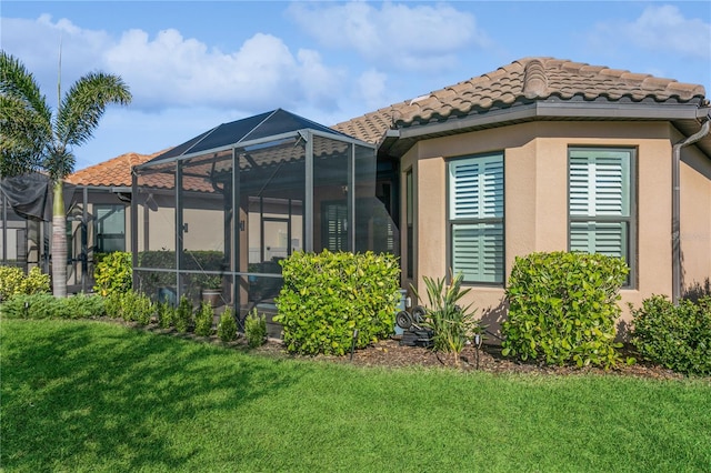 back of property featuring glass enclosure and a yard