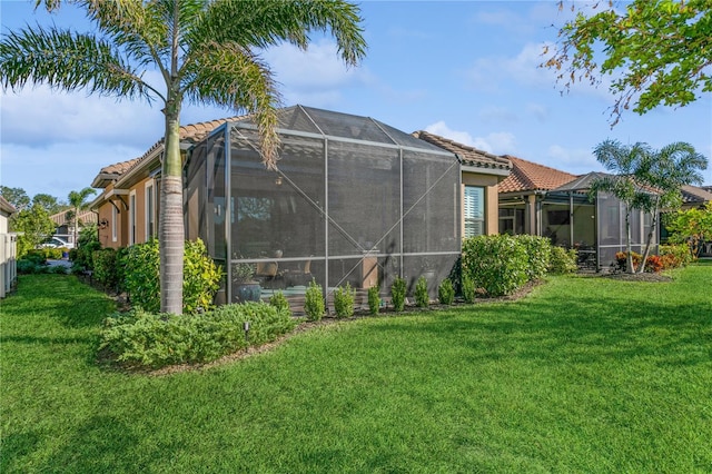 rear view of property featuring a lanai and a lawn