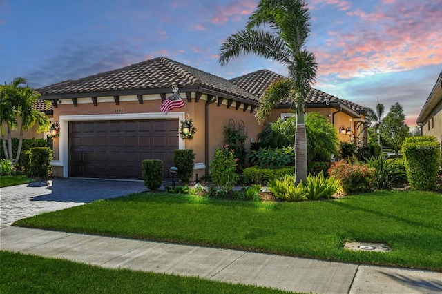 mediterranean / spanish-style house featuring a yard and a garage