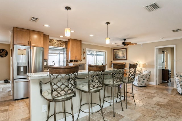 kitchen with a breakfast bar area, stainless steel fridge, a kitchen island, and hanging light fixtures