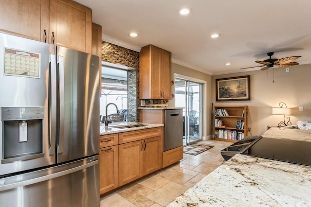 kitchen with light stone countertops, appliances with stainless steel finishes, ceiling fan, and sink