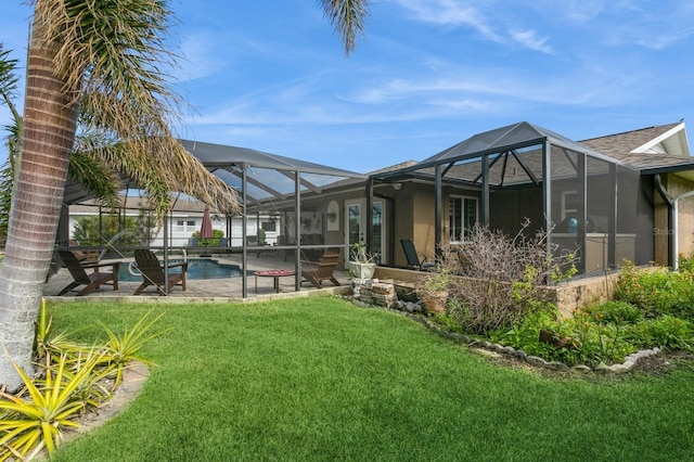 rear view of property featuring a yard, a patio area, and a lanai