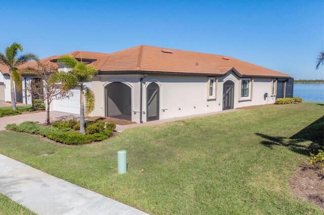 view of front of house featuring a garage, a water view, and a front lawn