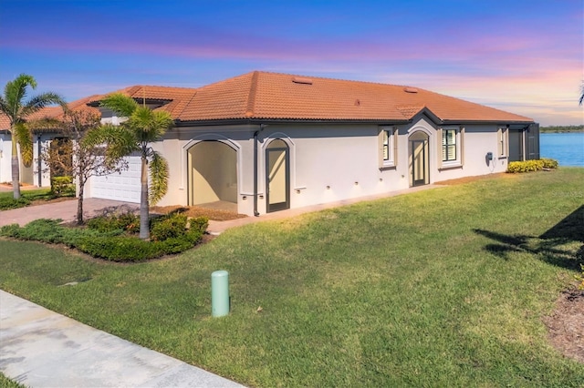 view of front of home with a yard, a water view, and a garage