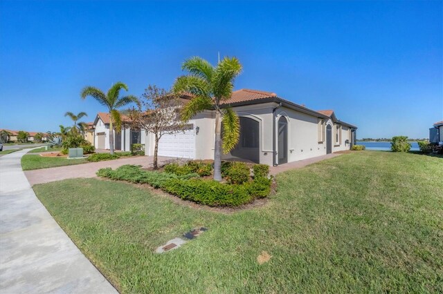 view of side of property with a lawn, a water view, and a garage