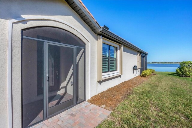 view of exterior entry with a lawn and a water view