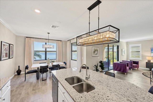 kitchen featuring pendant lighting, a water view, sink, stainless steel dishwasher, and white cabinetry