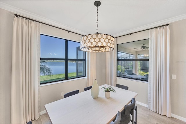 dining room featuring a water view, ornamental molding, ceiling fan with notable chandelier, and light wood-type flooring