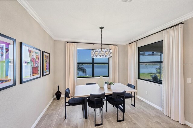 dining area featuring crown molding, light wood-type flooring, and an inviting chandelier