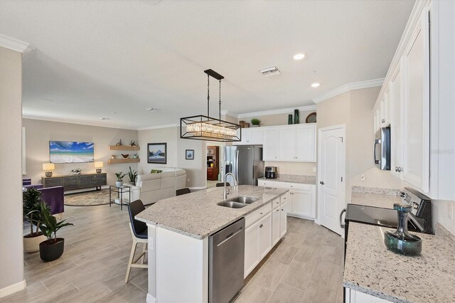 kitchen featuring hanging light fixtures, crown molding, a kitchen island with sink, white cabinets, and appliances with stainless steel finishes