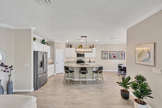 kitchen with pendant lighting, a breakfast bar, ornamental molding, an island with sink, and appliances with stainless steel finishes