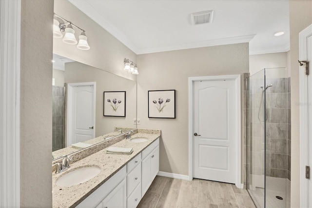 bathroom featuring tiled shower, wood-type flooring, crown molding, and vanity