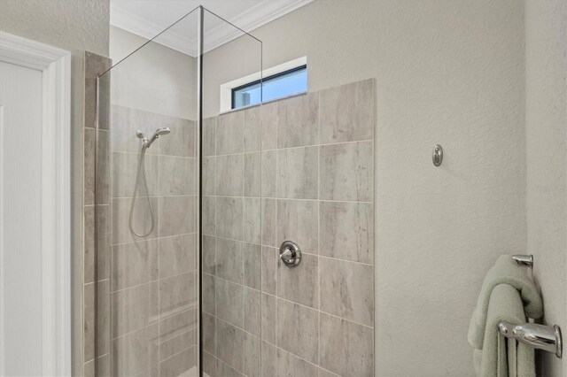 bathroom with a tile shower and ornamental molding