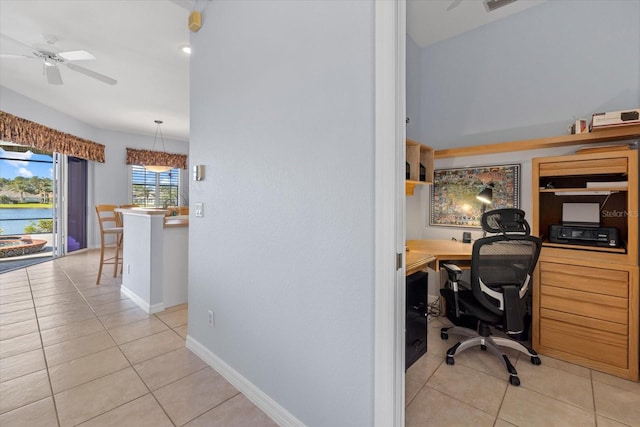 tiled office space featuring ceiling fan and a water view