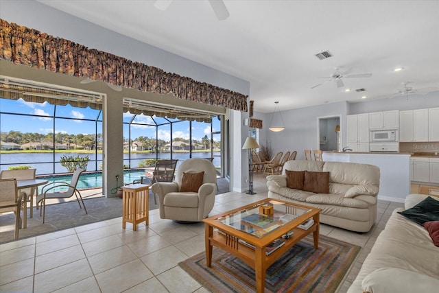 tiled living room with ceiling fan and a water view