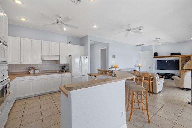 kitchen with white cabinets, white fridge, light tile patterned flooring, and sink