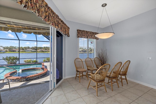 dining room featuring light tile patterned flooring, a water view, and a healthy amount of sunlight