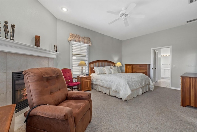 bedroom featuring light carpet, ceiling fan, and a tiled fireplace