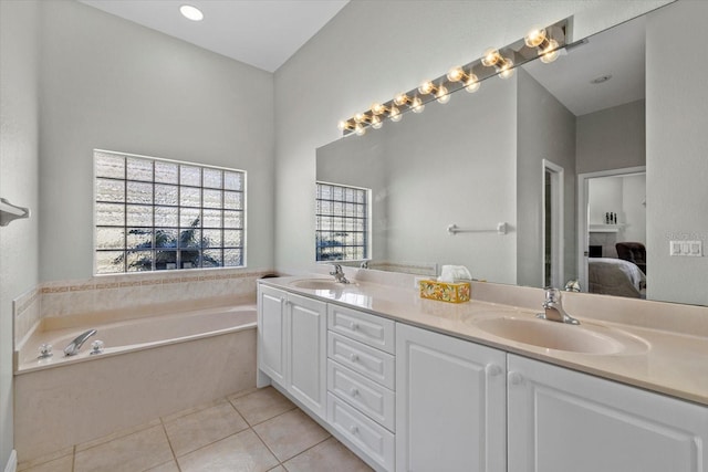 bathroom with a tile fireplace, vanity, tile patterned floors, and a washtub