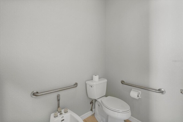 bathroom with tile patterned flooring, toilet, and a bidet