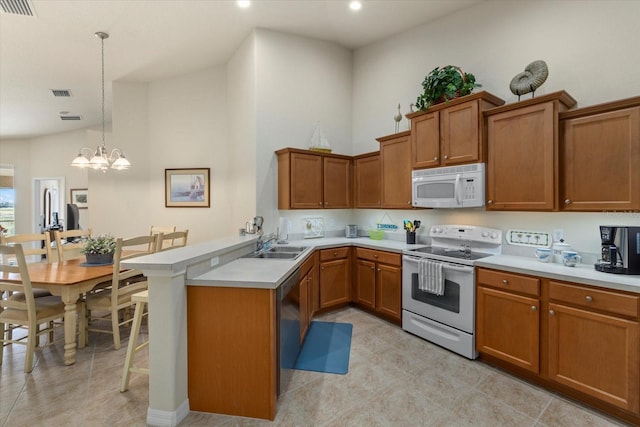 kitchen featuring kitchen peninsula, white appliances, sink, an inviting chandelier, and hanging light fixtures