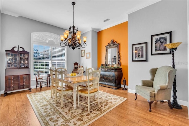 dining space featuring crown molding, wood-type flooring, and an inviting chandelier