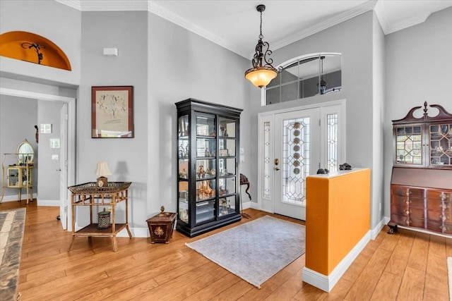 entryway featuring a high ceiling, ornamental molding, and hardwood / wood-style floors