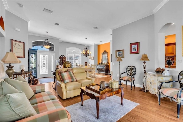 living room featuring a chandelier, light wood-type flooring, and crown molding