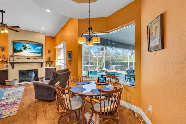 dining room featuring hardwood / wood-style floors, ceiling fan with notable chandelier, and vaulted ceiling