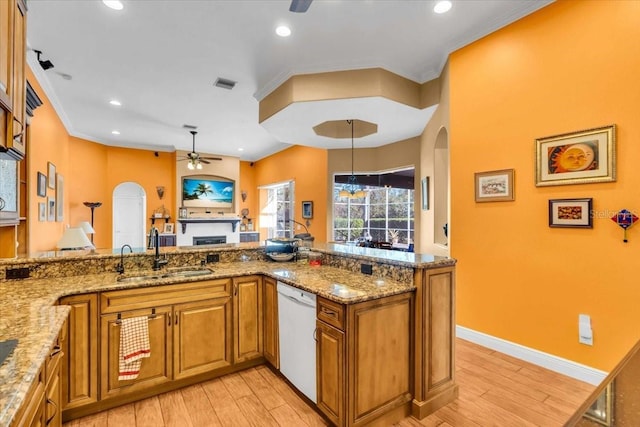 kitchen with light stone countertops, sink, hanging light fixtures, white dishwasher, and light wood-type flooring