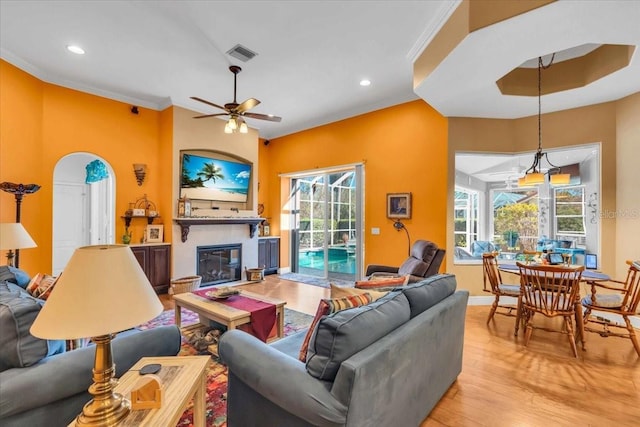 living room with light wood-type flooring, ceiling fan, and crown molding