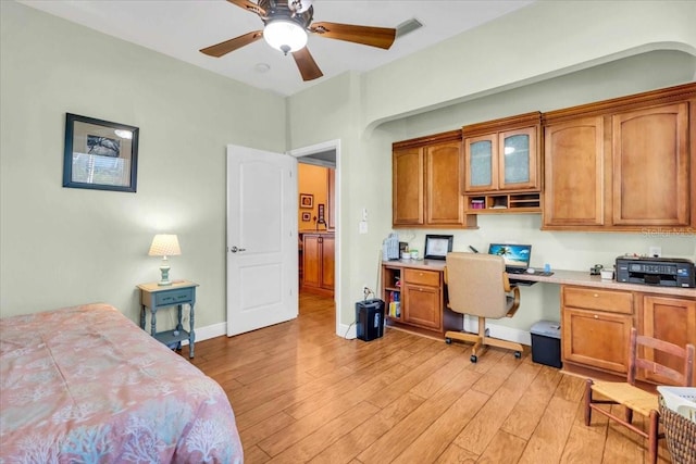 bedroom with light wood-type flooring, ceiling fan, and built in desk