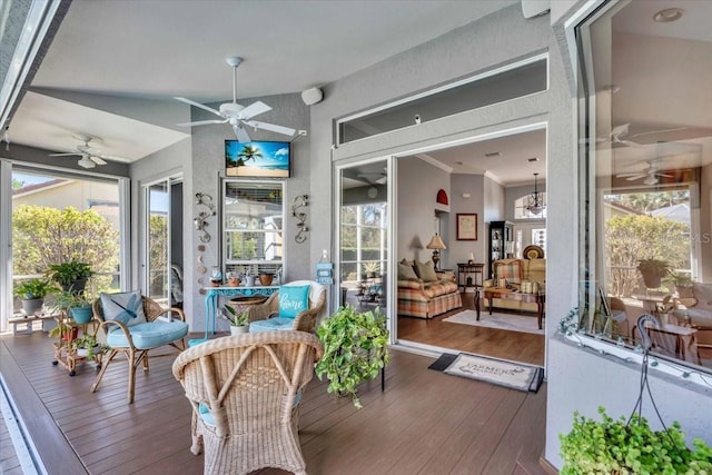 sunroom with ceiling fan with notable chandelier and vaulted ceiling