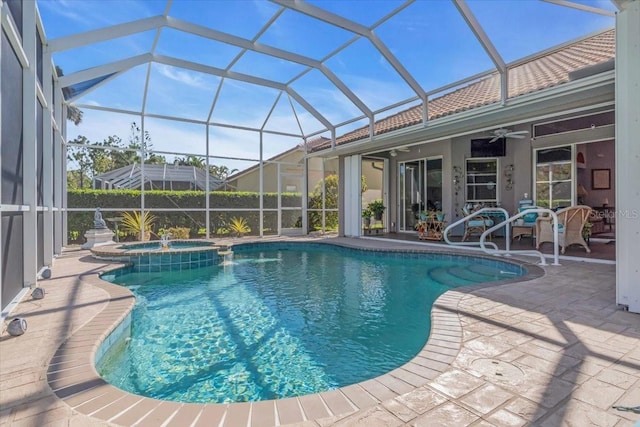 view of swimming pool with glass enclosure, ceiling fan, a patio, and an in ground hot tub