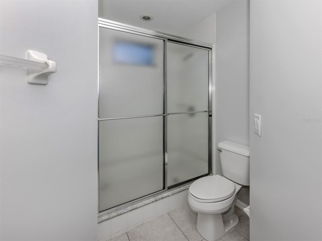 bathroom featuring tile patterned floors, a shower with shower door, and toilet