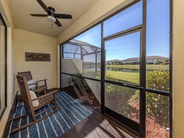 sunroom with ceiling fan and a water view