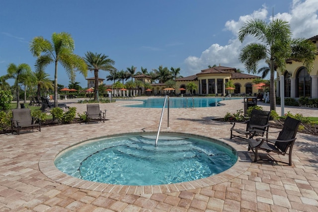 view of swimming pool featuring a patio and a hot tub