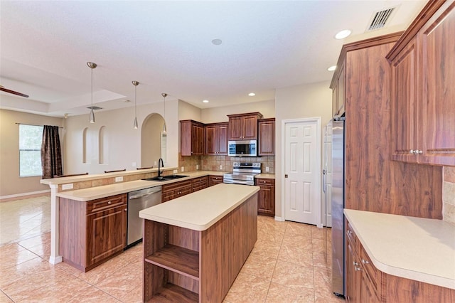 kitchen featuring a center island, hanging light fixtures, stainless steel appliances, kitchen peninsula, and decorative backsplash