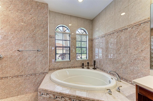 bathroom with vanity, a relaxing tiled tub, and tile walls