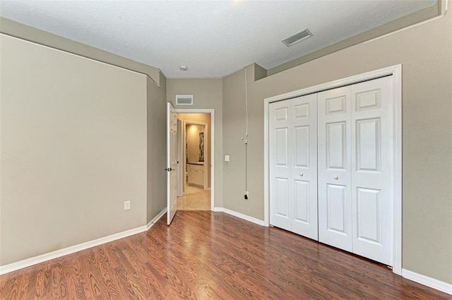 unfurnished bedroom featuring a textured ceiling, a closet, and dark wood-type flooring