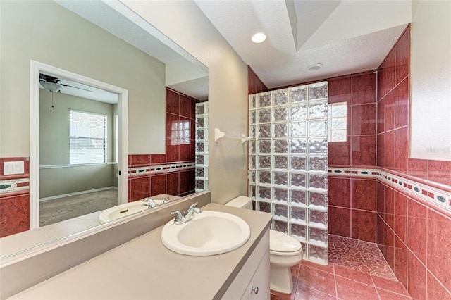 bathroom with a tile shower, a textured ceiling, ceiling fan, tile walls, and tile patterned flooring