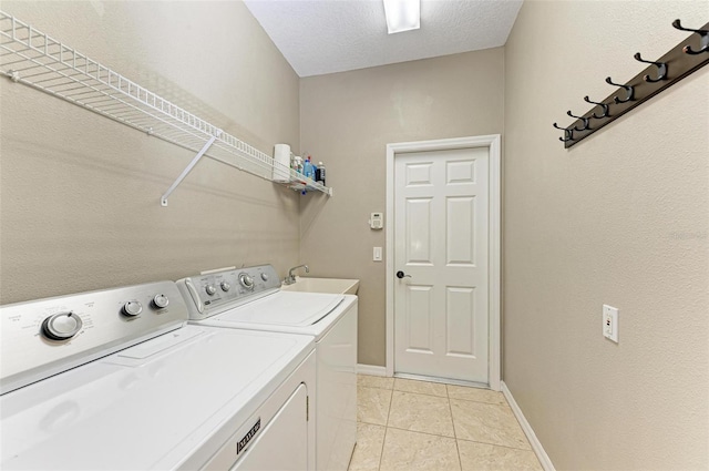 laundry room featuring a textured ceiling, separate washer and dryer, sink, and light tile patterned floors