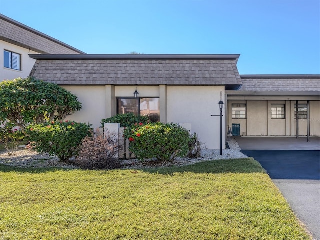 1708 Bonitas Cir Unit 1726A, Venice, FL 34293 - view of home's exterior with mansard roof, stucco siding, roof with shingles, and a yard