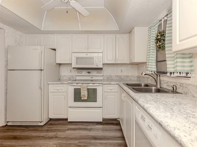 kitchen with sink, a textured ceiling, white appliances, white cabinets, and hardwood / wood-style flooring