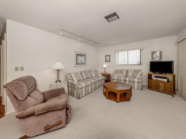 living room with carpet, track lighting, and a textured ceiling