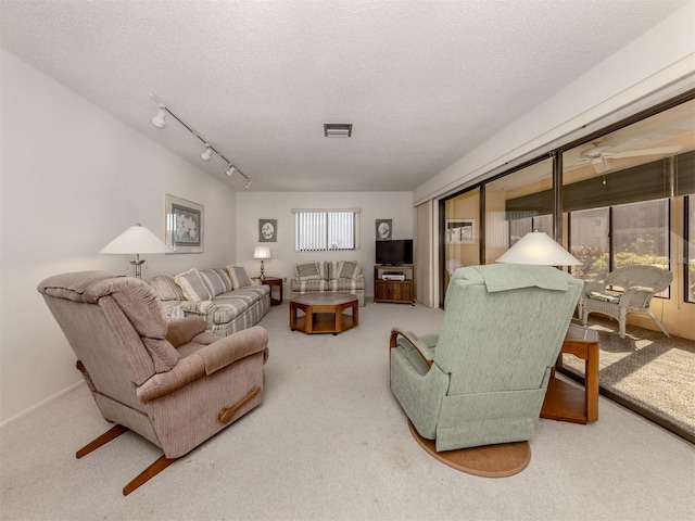 carpeted living room featuring ceiling fan, rail lighting, a healthy amount of sunlight, and a textured ceiling