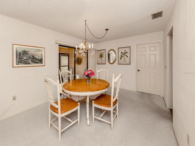 carpeted dining area featuring a chandelier and a textured ceiling